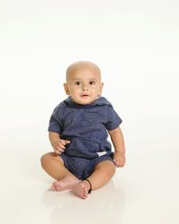 Portrait of cute baby sitting against white background