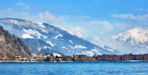 Scenic view of sea by snowcapped mountain against sky