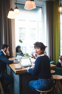 Portrait of smiling female professional sitting with laptop at table in office