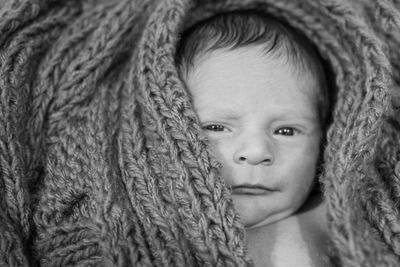 Portrait of cute baby boy lying in knitted wool at home