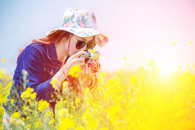 Woman photographing with camera at rape field