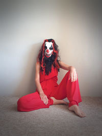 Young woman sitting against wall