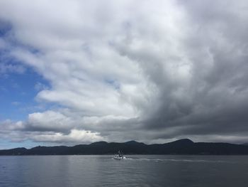 Boats in sea against cloudy sky