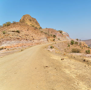 Scenic view of arid landscape against clear blue sky