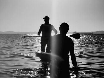 Rear view of shirtless man standing in sea against sky