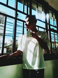 Full length of young man drinking glass window