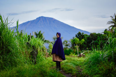 Woman standing on field against sky