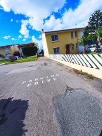 Road by building against sky on sunny day