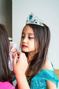 Portrait of mother fixing daughter makeup who is wearing costume.