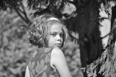 Rear view portrait of girl against tree on sunny day