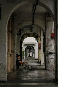 Side view of man sitting at entrance of building