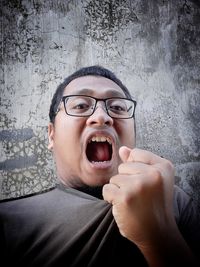 Portrait of woman shouting against wall