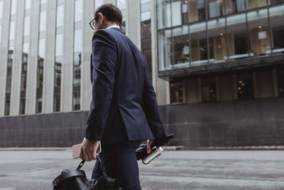 Side view of businessman with bag walking in city