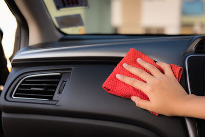 Cropped hand of woman cleaning car dashboard