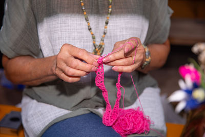 Senior woman knitting pink yarn, crafting hands at work, engaging in handmade crocheting