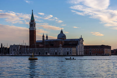 View of buildings at waterfront against cloudy sky