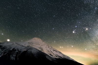 Scenic view of snowcapped mountains against sky at night