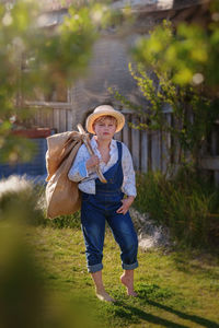 Pretty boy in a straw hat walks with a bag on his shoulders around the farm. book story 