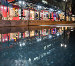 Reflection of illuminated building in puddle at night