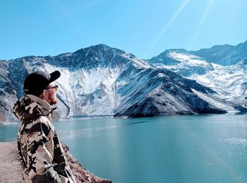 Woman on snowcapped mountain by lake against sky