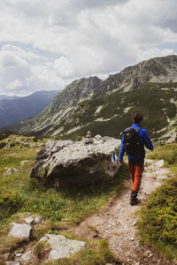 Rear view of man standing on mountain against sky