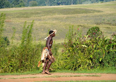 Side view of tribal man walking on field by plants