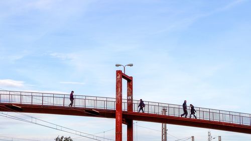 People standing on footbridge against sky