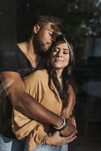 Man embracing woman standing with eyed closed at home