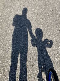 Shadow of man with umbrella standing on road