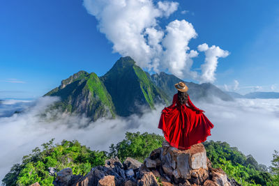 Rear view of woman standing on mountain against sky