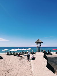 People on beach against blue sky