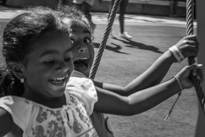 Cheerful girls playing on swing at park