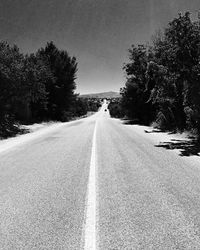 Surface level of road amidst trees in city against sky