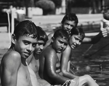 Portrait of shirtless boy sitting in swimming pool