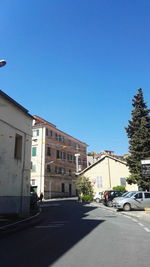 Road against clear blue sky in city