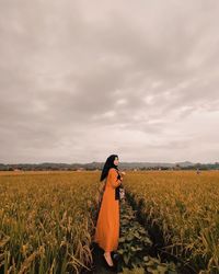 Woman standing on field against sky