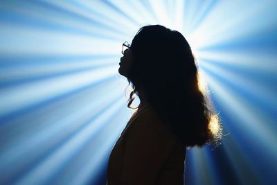 Side view of woman standing against light beams