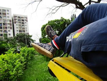 Man holding yellow umbrella by plants in city