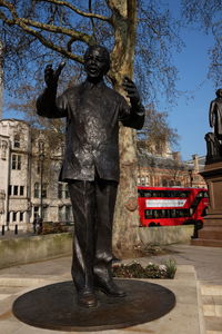 Statue by building in city against sky