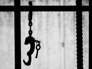 Close-up of handcuffs and keys hanging from security bars at prison