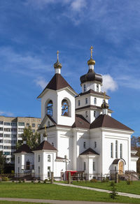 Church by building against blue sky