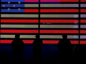 Silhouette police force standing against american flag at times square