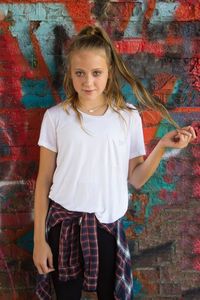 Portrait of girl standing against wall