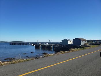 Road by sea against clear blue sky