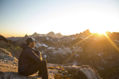 Side view of mountaineer watching sunset from high mountain pass.