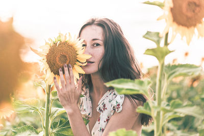 Portrait of woman with sunflower amidst plants