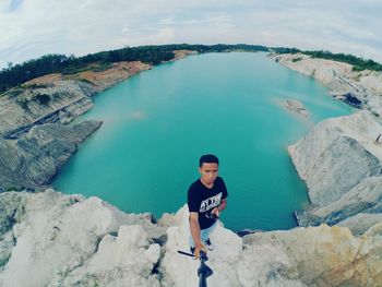 Man standing on rocks against turquoise lake