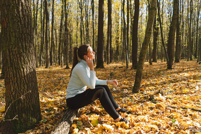 Beautiful girl listening to music and doing fitness or yoga in nature