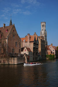 Buildings by river against sky