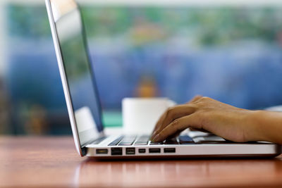 Close-up of person using laptop on table